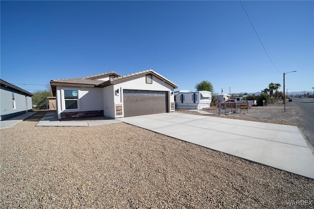 view of front of home with concrete driveway, an attached garage, a tiled roof, and stucco siding