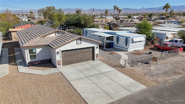 view of front of house featuring an attached garage, a mountain view, a tile roof, fence, and driveway