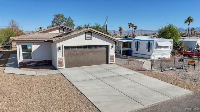 ranch-style home with a garage, fence, driveway, stone siding, and stucco siding