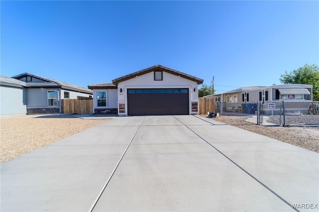 view of front of house with an attached garage, driveway, fence, and stucco siding