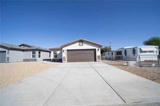 view of front of property featuring an attached garage, fence, concrete driveway, a gate, and stucco siding