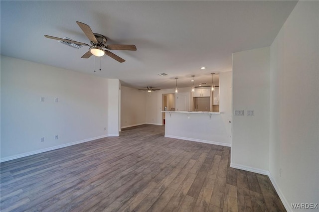 unfurnished living room with visible vents, dark wood finished floors, baseboards, and ceiling fan