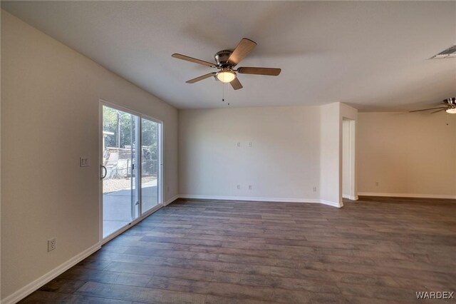 empty room with baseboards, dark wood-type flooring, visible vents, and a ceiling fan