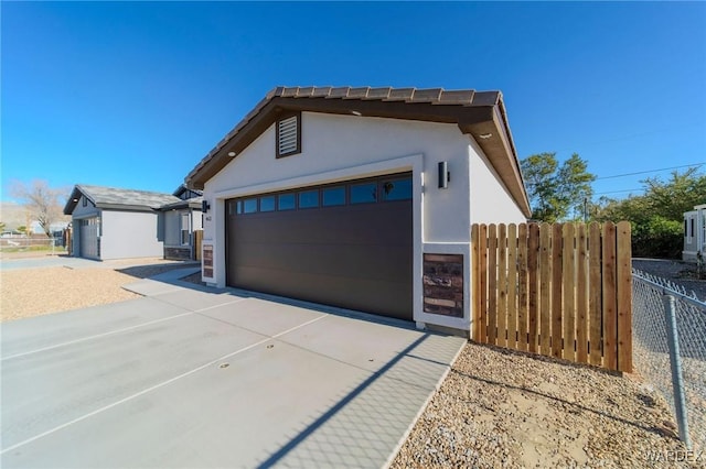 exterior space featuring fence, driveway, and stucco siding