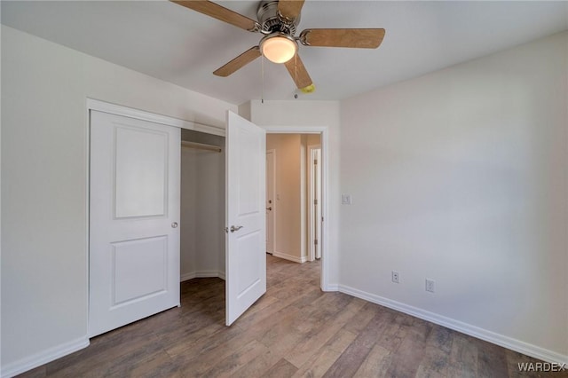 unfurnished bedroom with ceiling fan, a closet, baseboards, and wood finished floors