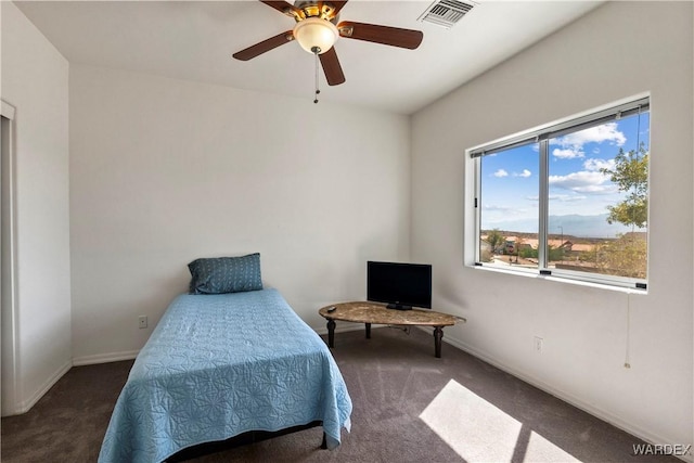 bedroom with ceiling fan, dark colored carpet, visible vents, and baseboards