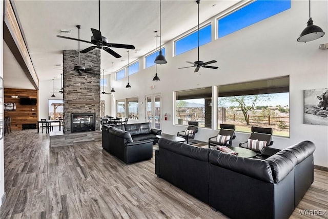 living area with light wood-type flooring, a fireplace, visible vents, and a ceiling fan