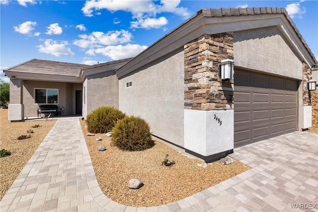 view of front facade with stone siding, an attached garage, and stucco siding