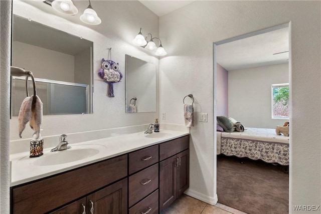 ensuite bathroom featuring connected bathroom, tile patterned floors, a sink, and double vanity