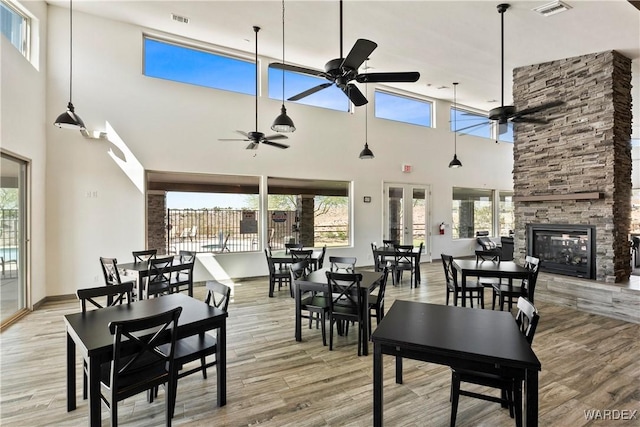 dining area with a ceiling fan, a fireplace, visible vents, and light wood-style floors