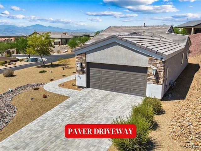 view of front of home featuring a mountain view, a tile roof, stone siding, decorative driveway, and stucco siding