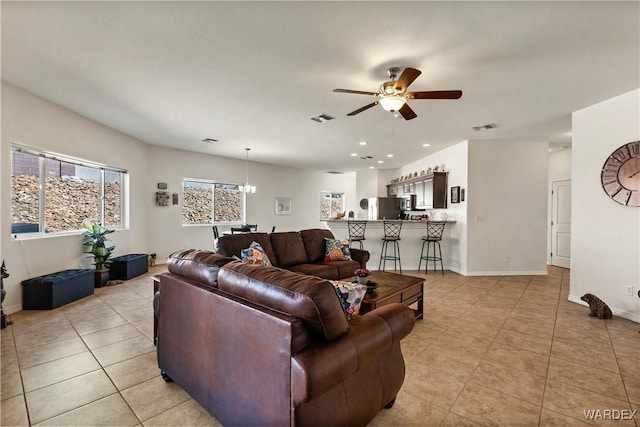 living area with light tile patterned floors, baseboards, visible vents, and a ceiling fan