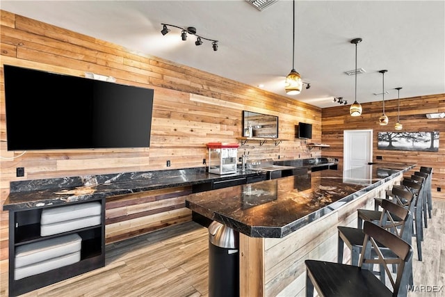 kitchen with dark countertops, hanging light fixtures, a kitchen island, and wooden walls