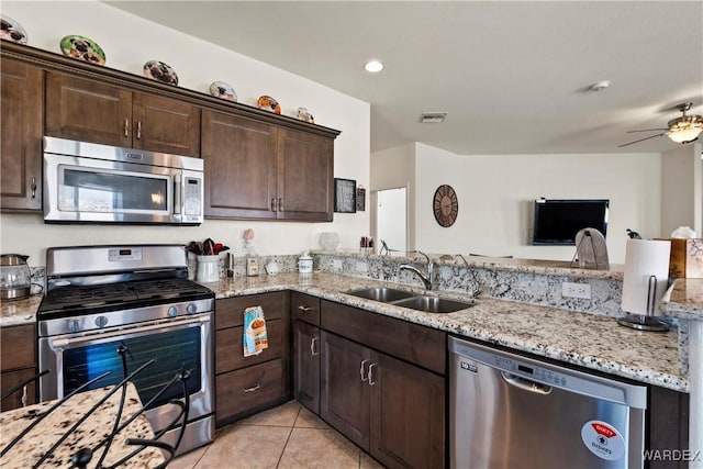 kitchen with light stone counters, light tile patterned flooring, a sink, visible vents, and appliances with stainless steel finishes