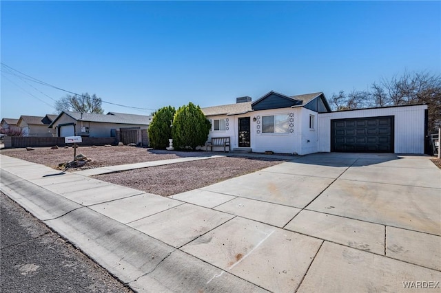 view of front of home with a chimney, concrete driveway, a garage, and fence