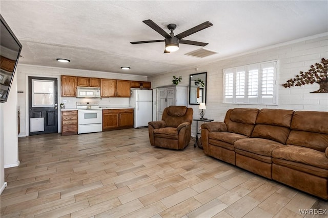 living room with visible vents, ceiling fan, wood finish floors, and ornamental molding