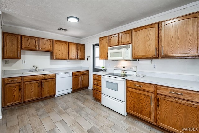 kitchen with white appliances, visible vents, a sink, light countertops, and brown cabinets