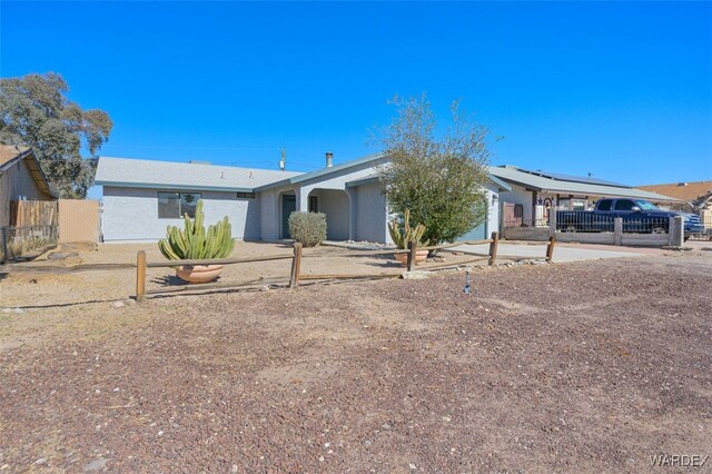 single story home with a fenced front yard, concrete driveway, and stucco siding