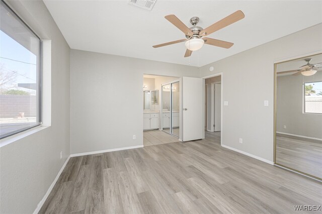 unfurnished bedroom with light wood-style floors, visible vents, connected bathroom, and baseboards