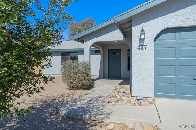 view of exterior entry featuring a garage and stucco siding