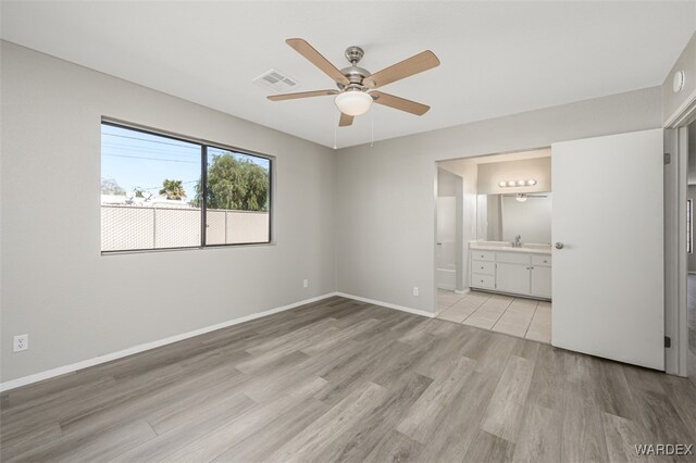 unfurnished bedroom featuring visible vents, baseboards, ceiling fan, ensuite bathroom, and light wood-style floors