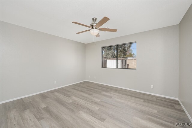 spare room with ceiling fan, light wood finished floors, and baseboards