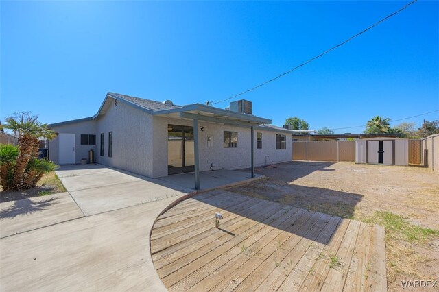 rear view of house with a patio, a fenced backyard, an outbuilding, a shed, and stucco siding