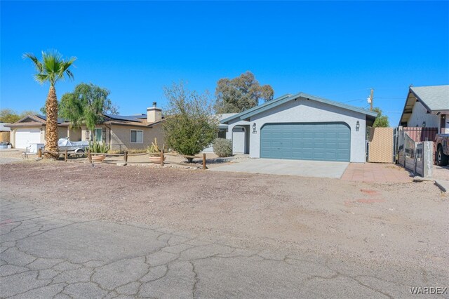 ranch-style home with a garage, fence, concrete driveway, and stucco siding