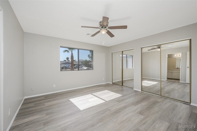 unfurnished bedroom with multiple closets, ceiling fan, light wood-style flooring, and baseboards