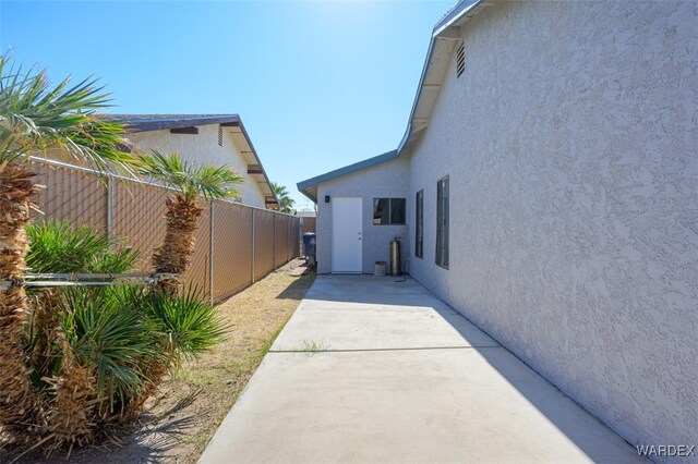 view of side of property with fence, a patio, and stucco siding