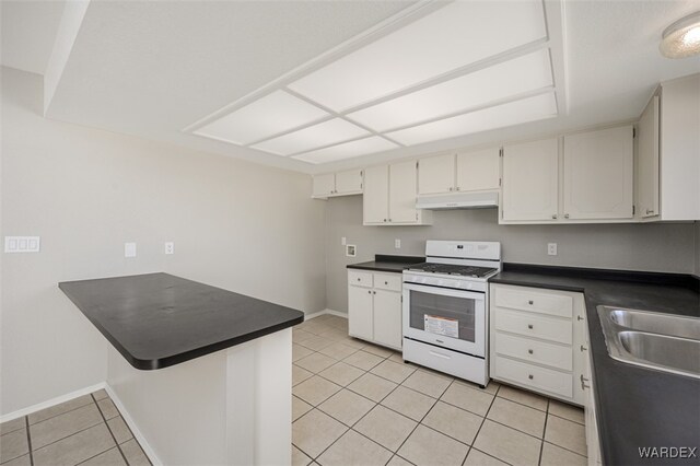 kitchen featuring under cabinet range hood, gas range gas stove, dark countertops, and white cabinets