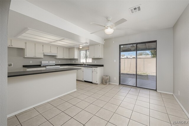 kitchen with a peninsula, white appliances, visible vents, white cabinetry, and dark countertops