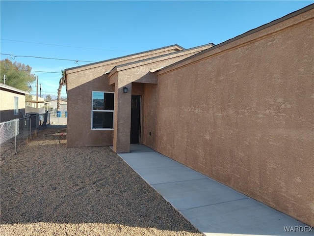 property entrance featuring fence and stucco siding