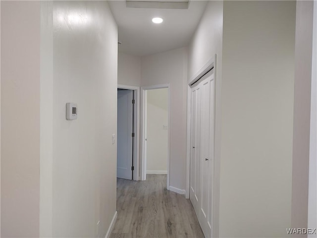 corridor featuring light wood-type flooring, baseboards, and recessed lighting