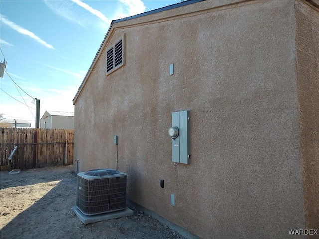 view of property exterior featuring central air condition unit, fence, and stucco siding