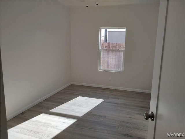 empty room with dark wood-style floors and baseboards