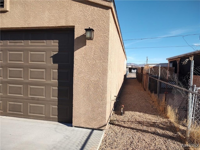 view of home's exterior featuring a garage, fence, and stucco siding