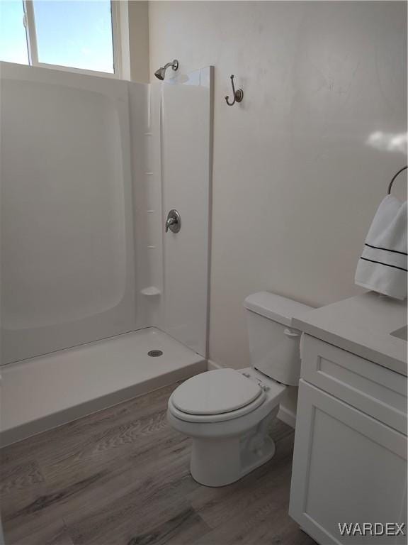 bathroom featuring vanity, a shower stall, toilet, and wood finished floors