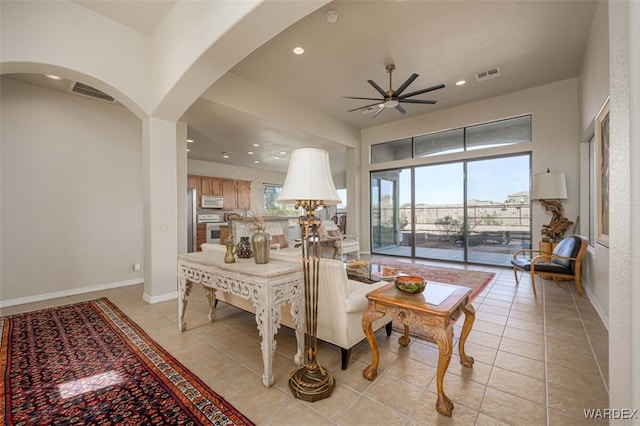 living area featuring arched walkways, light tile patterned flooring, visible vents, and baseboards