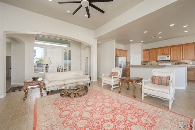 living area with arched walkways, light tile patterned floors, baseboards, and recessed lighting