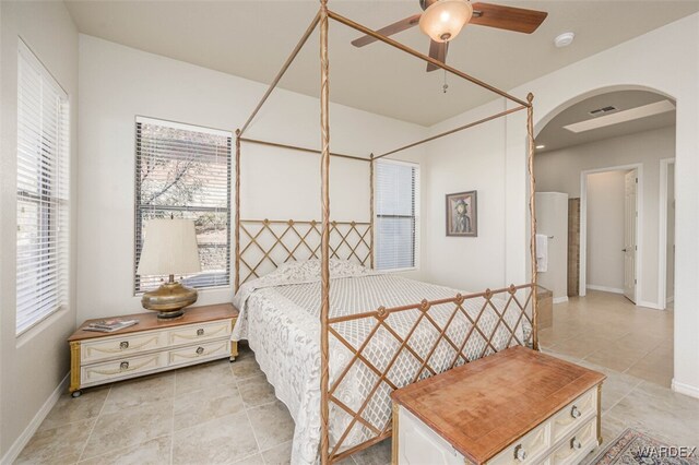 bedroom featuring arched walkways, ceiling fan, light tile patterned floors, visible vents, and baseboards