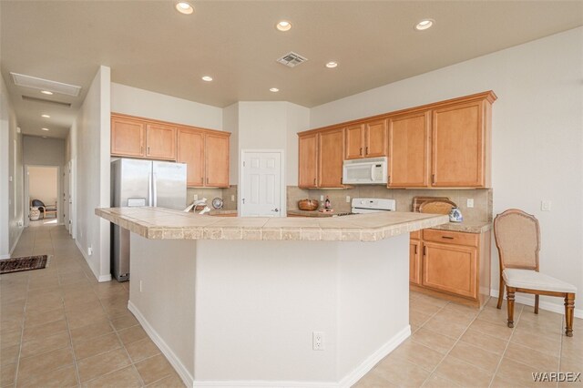 kitchen featuring light tile patterned floors, white appliances, an island with sink, and tasteful backsplash