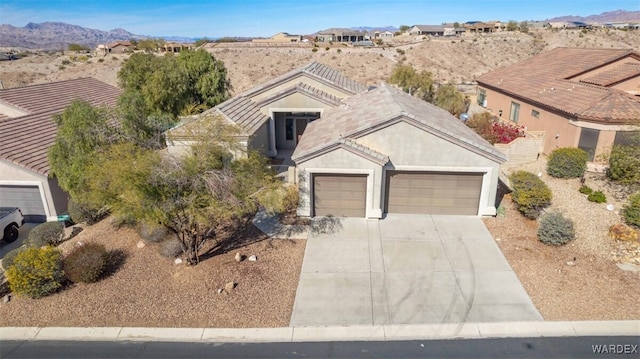 view of front of house with a mountain view, a garage, a tile roof, driveway, and stucco siding