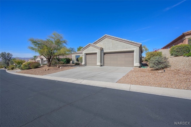 ranch-style house with concrete driveway, an attached garage, and stucco siding