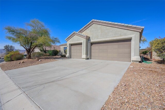 view of front of house with concrete driveway, an attached garage, a tiled roof, and stucco siding