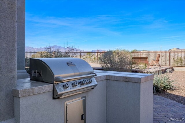 view of patio featuring a grill, fence, a mountain view, and area for grilling