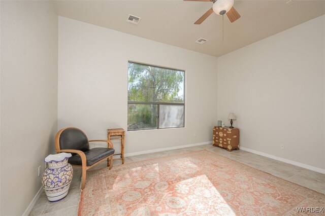 living area with a ceiling fan, visible vents, and baseboards