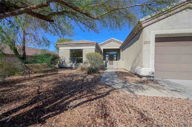 view of front of home with a garage, fence, and stucco siding