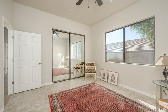 living area featuring light tile patterned floors, baseboards, and a ceiling fan