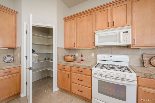 kitchen with light tile patterned floors, white appliances, and tasteful backsplash